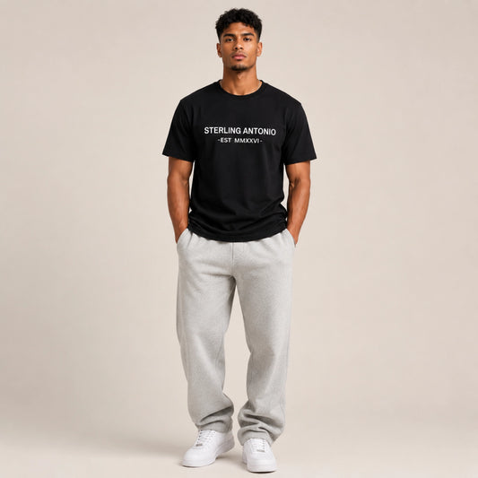 Man wearing a black t-shirt with text and gray sweatpants on a beige background