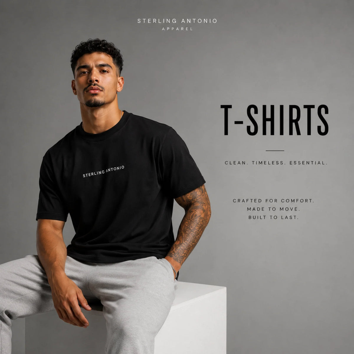 Male model wearing a black Sterling Antonio premium T-shirt with gray sweatpants in a modern studio, showcasing the Sterling Antonio T-Shirts collection of luxury streetwear essentials.