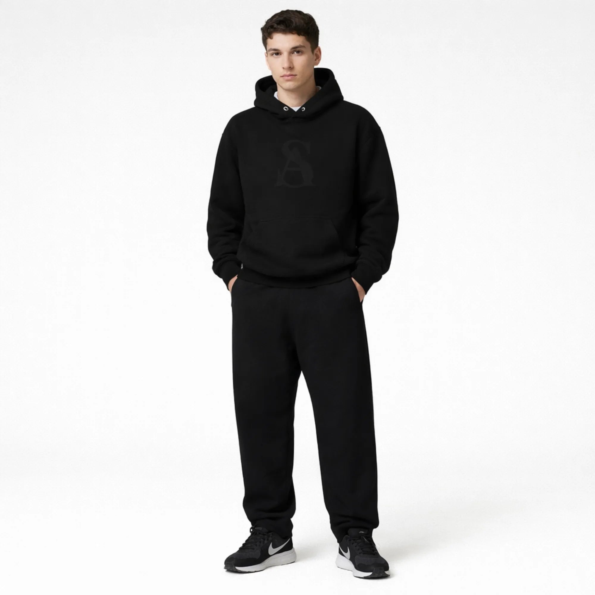 Person wearing a black hoodie and pants on a white background