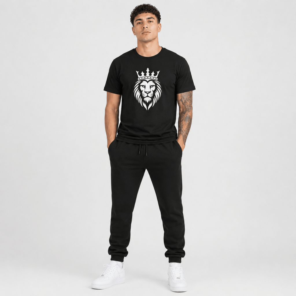 Male fashion model wearing a black t-shirt featuring a white crowned lion graphic with matching black sweatpants and white sneakers.