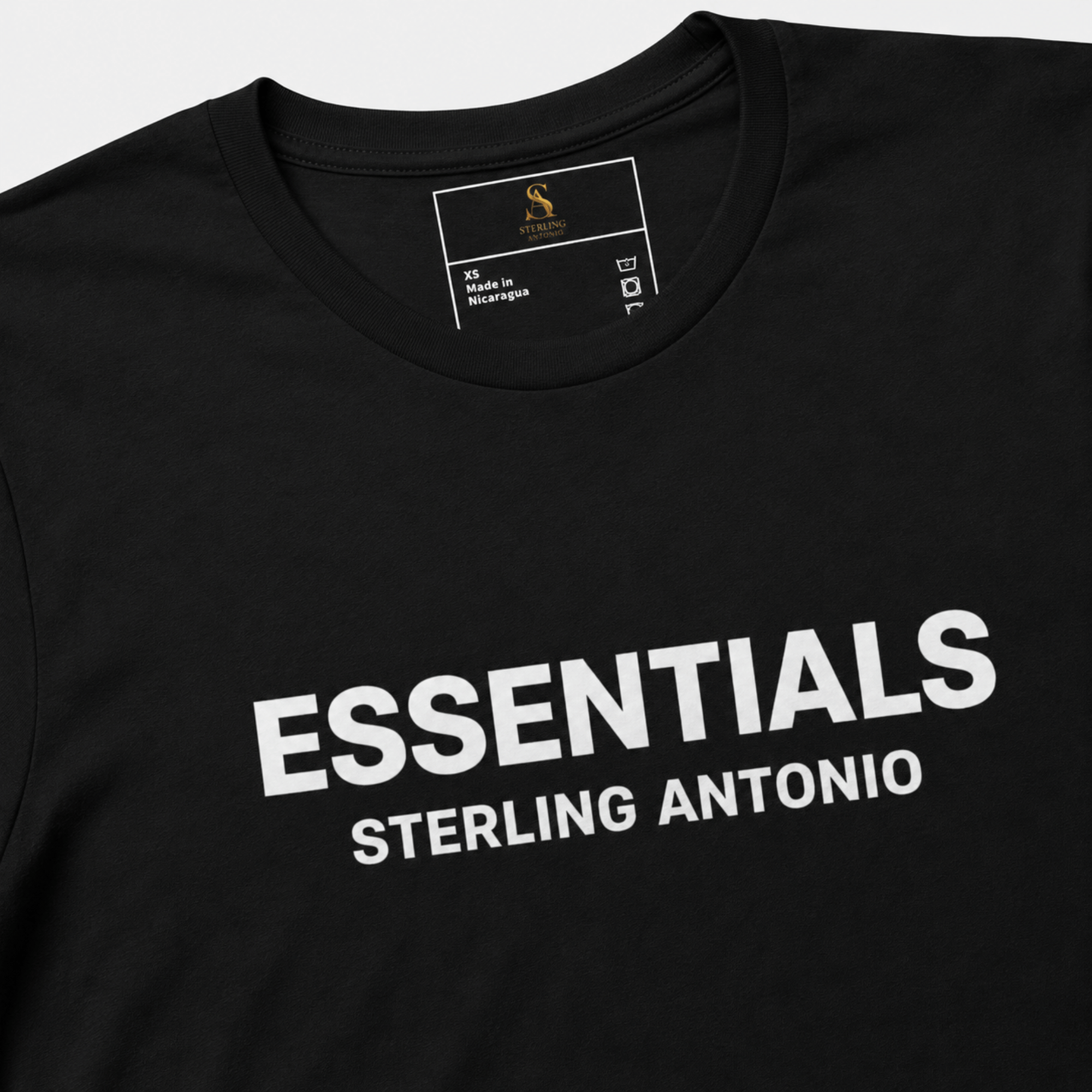 Close-up of a black Essentials Sterling Antonio cotton jersey t-shirt featuring bold white front print branding and premium neckline detailing.