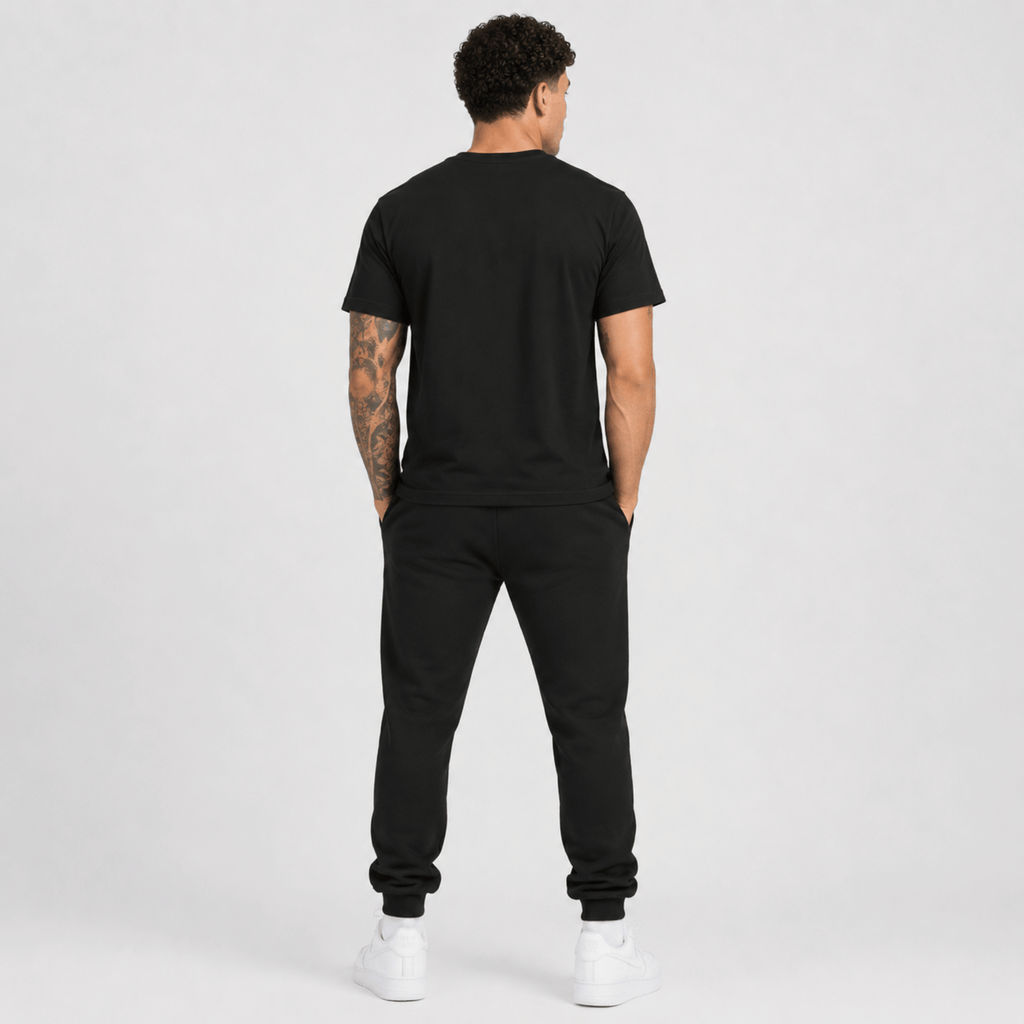 Rear view of a male fashion model wearing a black Sterling Antonio cotton jersey t-shirt with matching black sweatpants and white sneakers