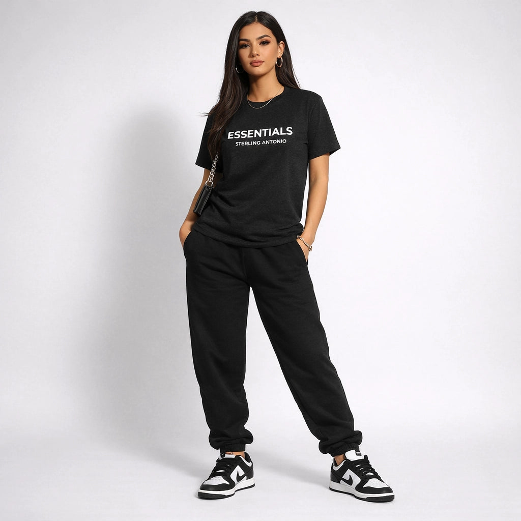 Woman wearing a black 'ESSENTIALS' t-shirt and pants on a white background