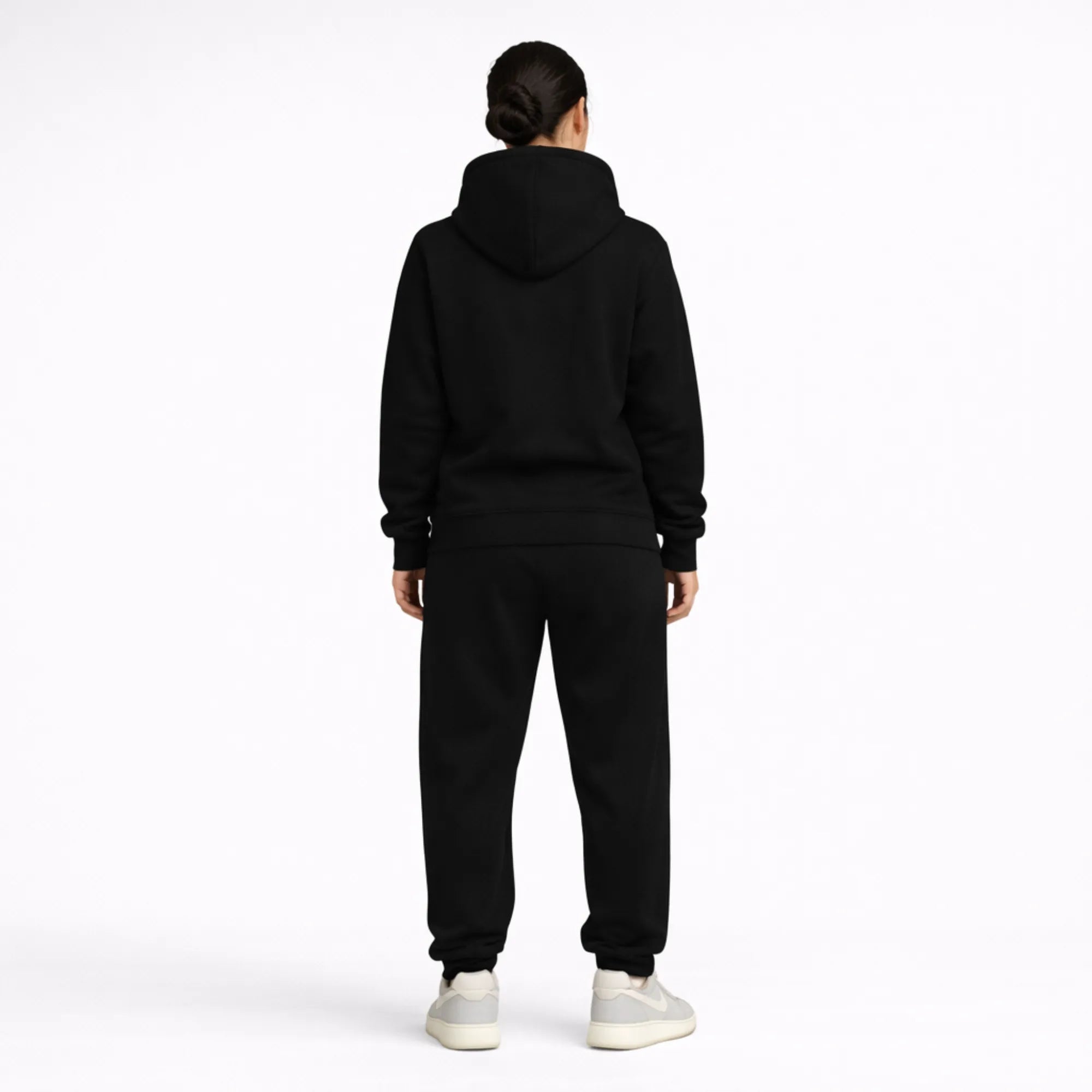 Person wearing a black hoodie and pants set on a white background