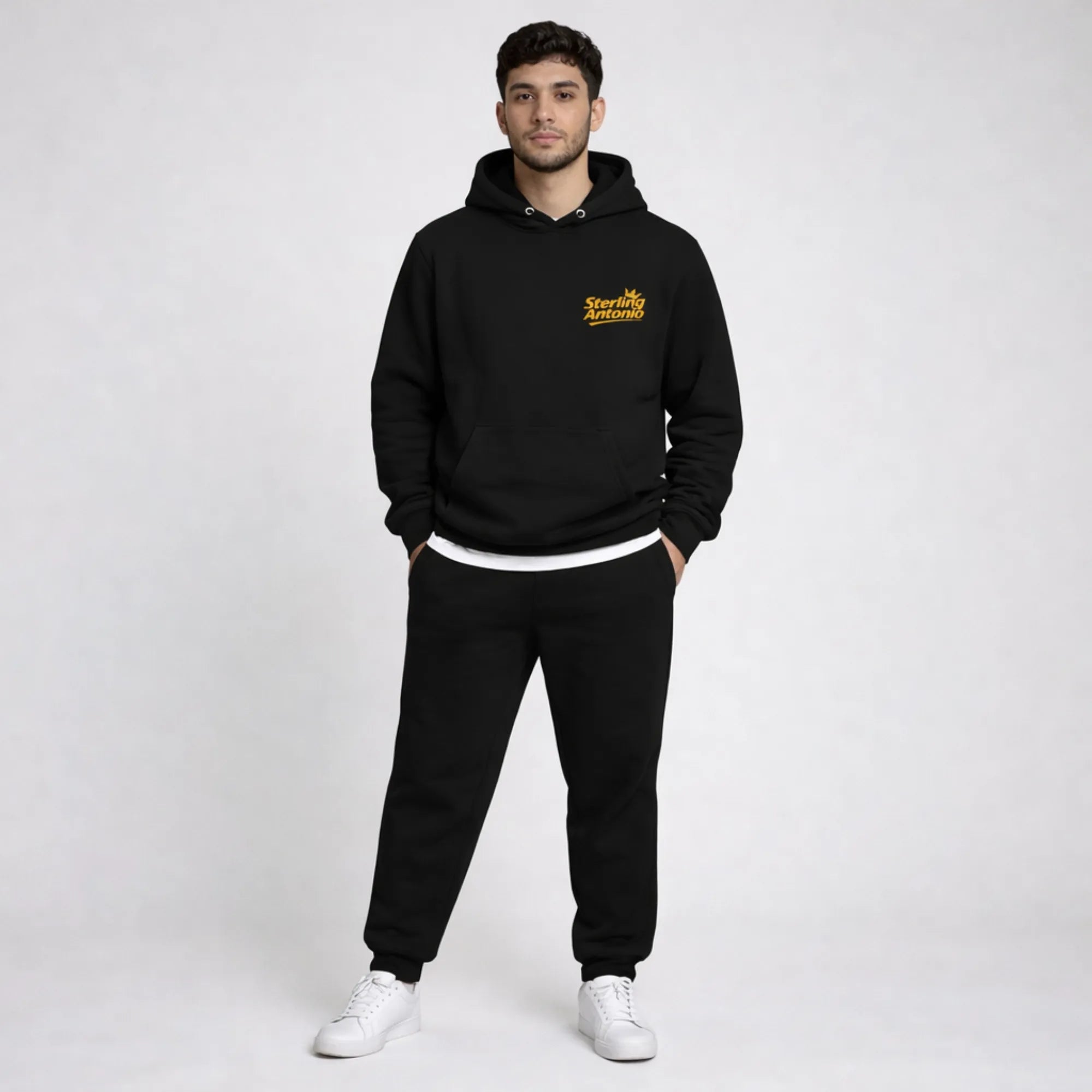 Man wearing a black hoodie and pants with a logo on a white background