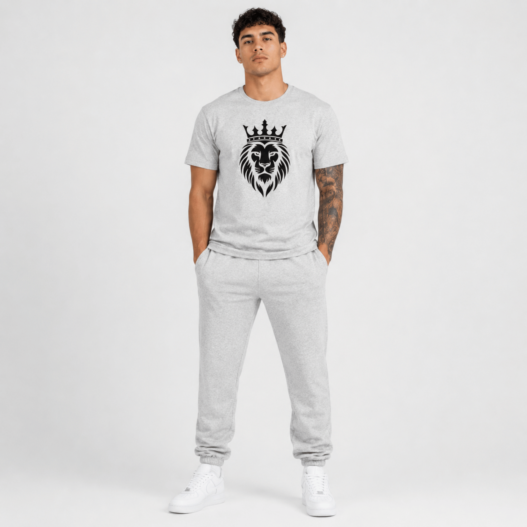 Male fashion model wearing a heather grey Sterling Antonio cotton jersey t-shirt featuring a black crowned lion graphic with matching grey sweatpants and white sneakers