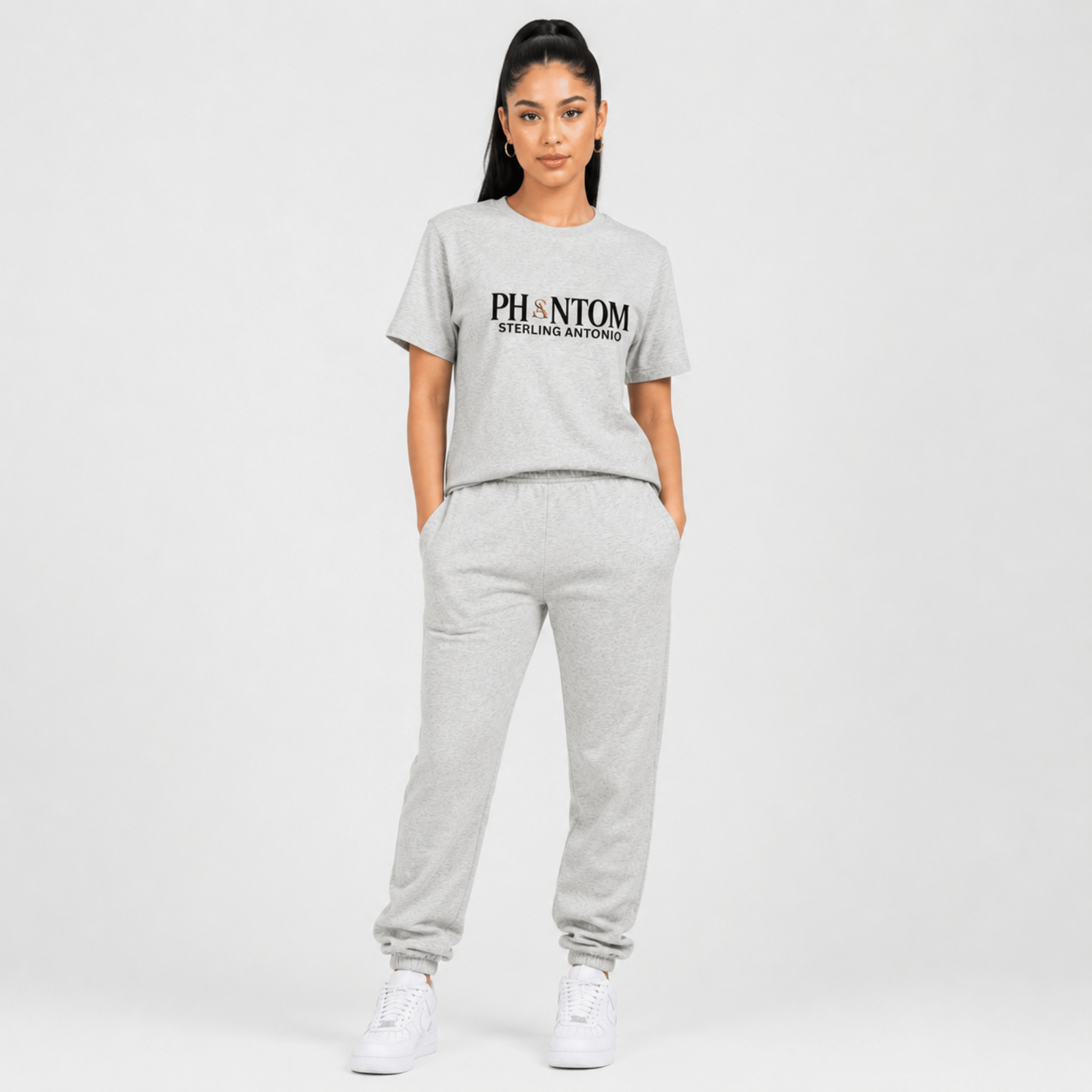 Female fashion model wearing a heather grey Phantom Sterling Antonio cotton jersey t-shirt with matching grey sweatpants and white sneakers on a light grey background