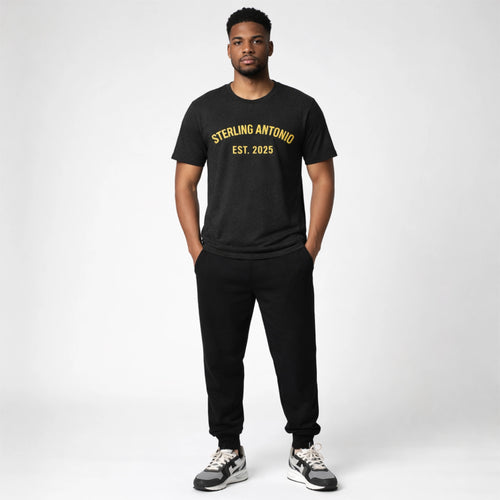 Man wearing a black t-shirt with text and black pants on a white background