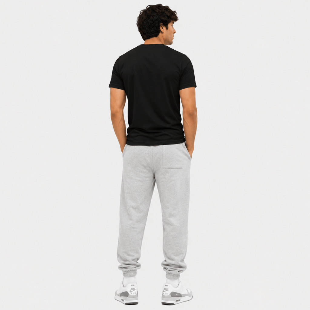 Man wearing a black t-shirt and gray sweatpants on a white background