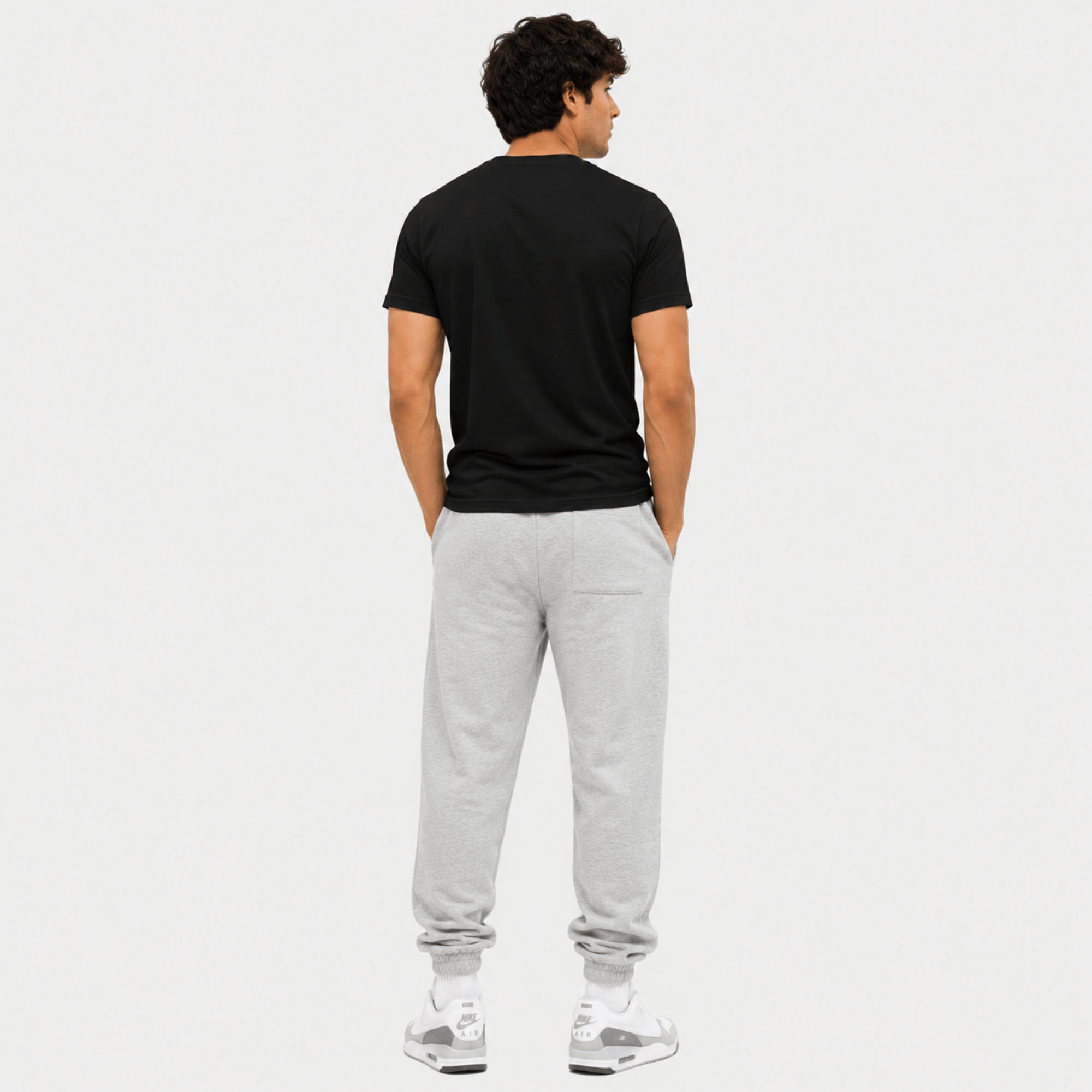 Man wearing a black t-shirt and gray sweatpants on a white background