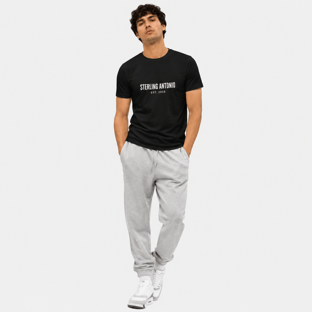 Man wearing a black t-shirt with 'STERLING ANTONIO' text and gray pants on a white background