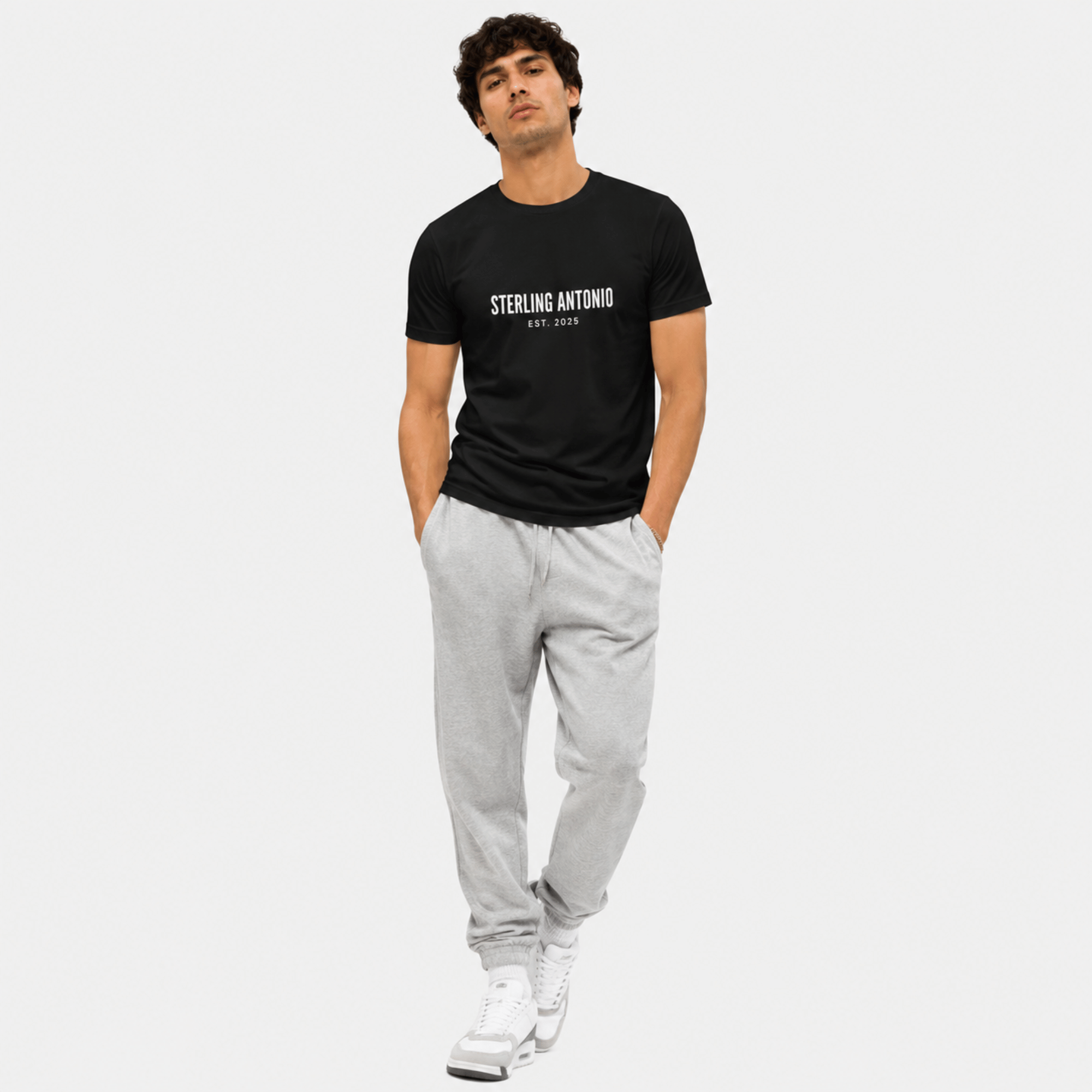 Man wearing a black t-shirt with 'STERLING ANTONIO' text and gray pants on a white background
