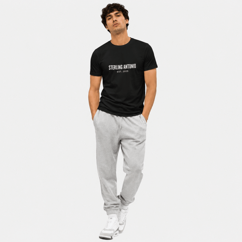 Man wearing a black t-shirt with 'STERLING ANTONIO' text and gray pants on a white background
