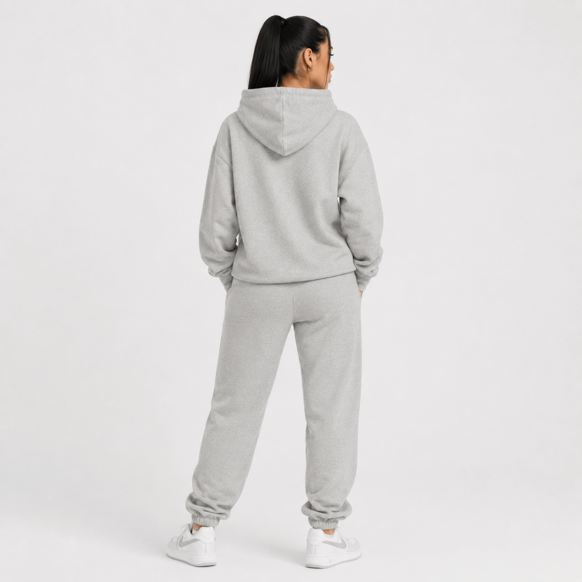 Person wearing a gray hoodie and pants set on a white background