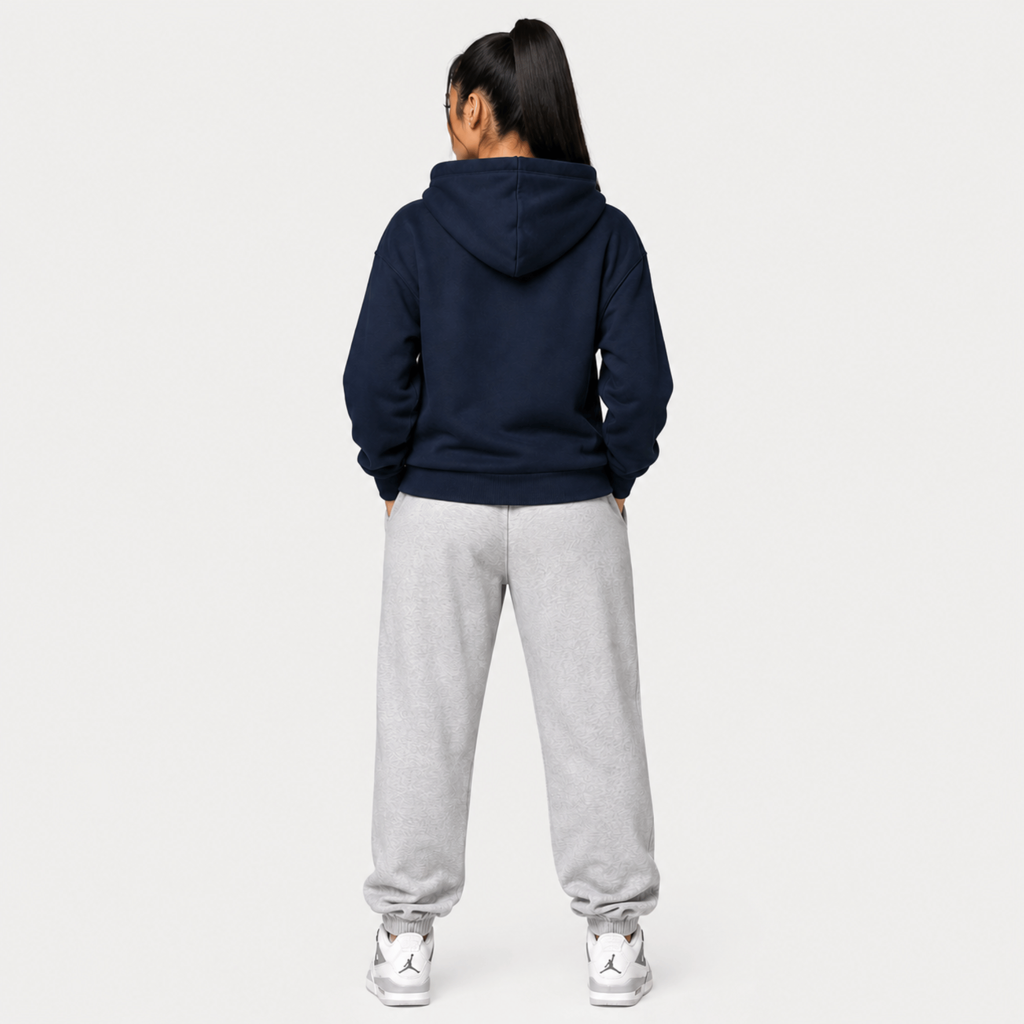 Person wearing a navy hoodie with a lion emblem on a light grey background rear view