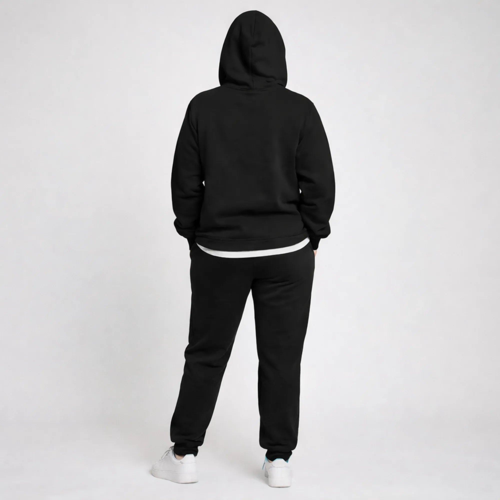 Person wearing a black hoodie and black pants on a white background