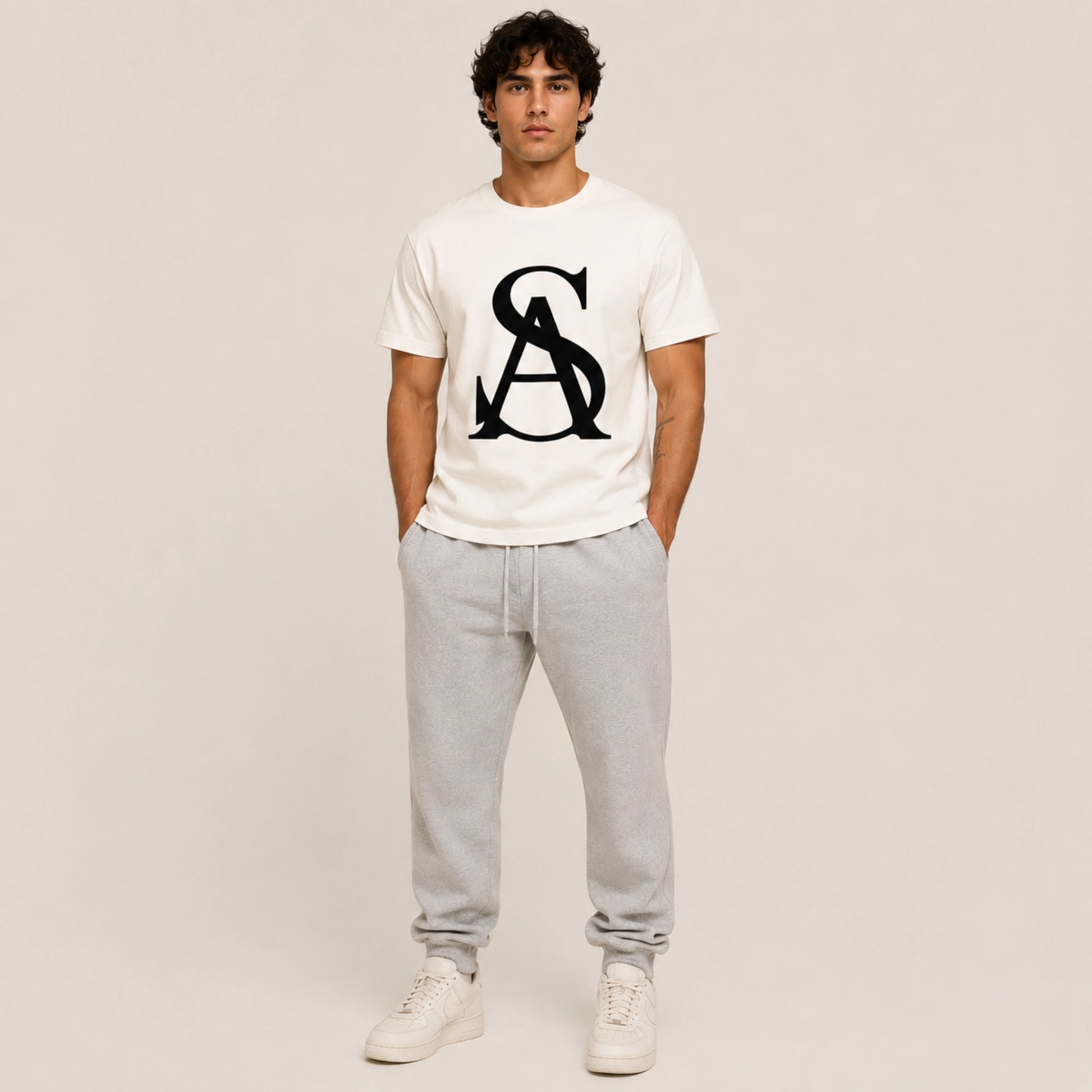Person wearing a white t-shirt with a logo and gray pants on a plain background