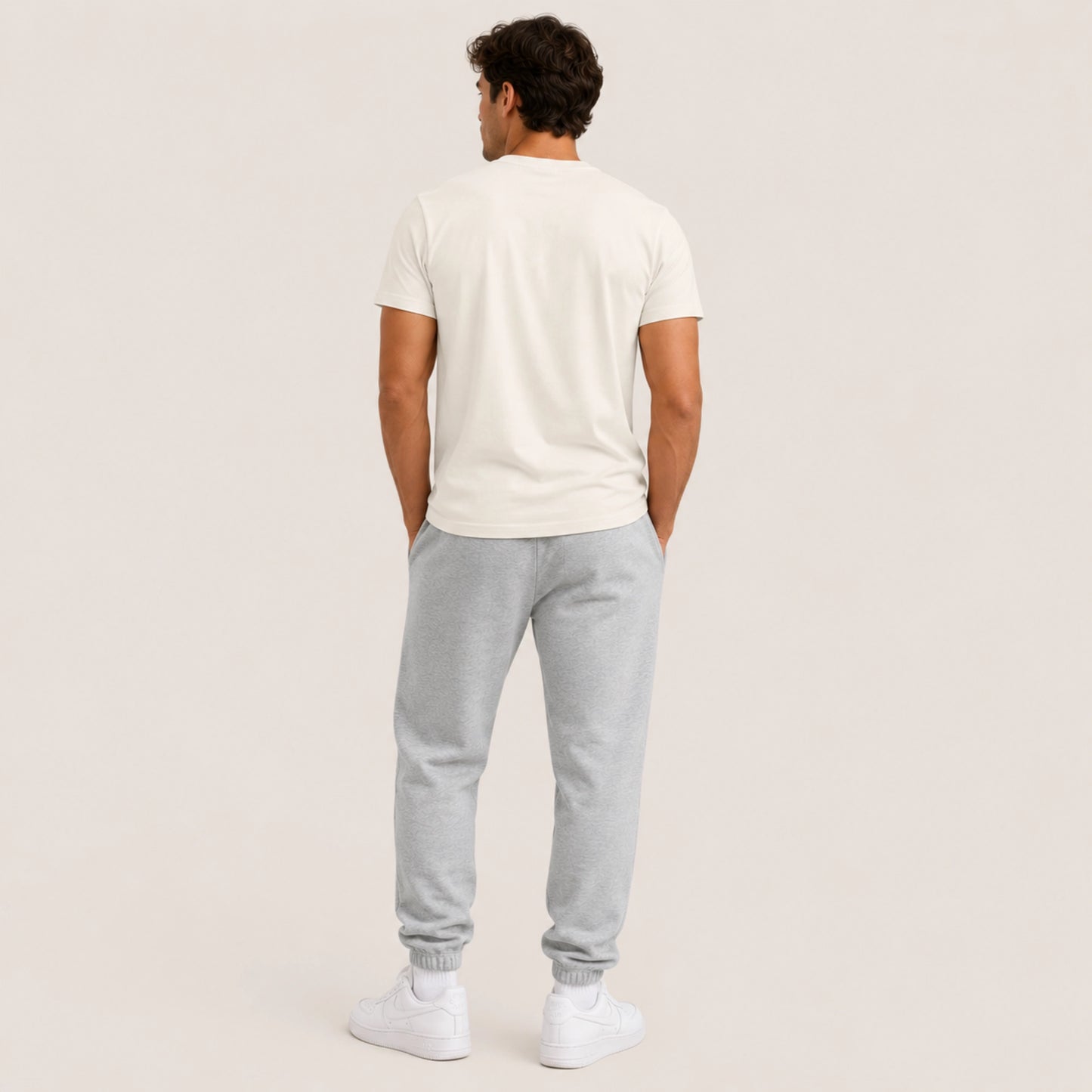 Man wearing a white t-shirt and gray sweatpants on a beige background