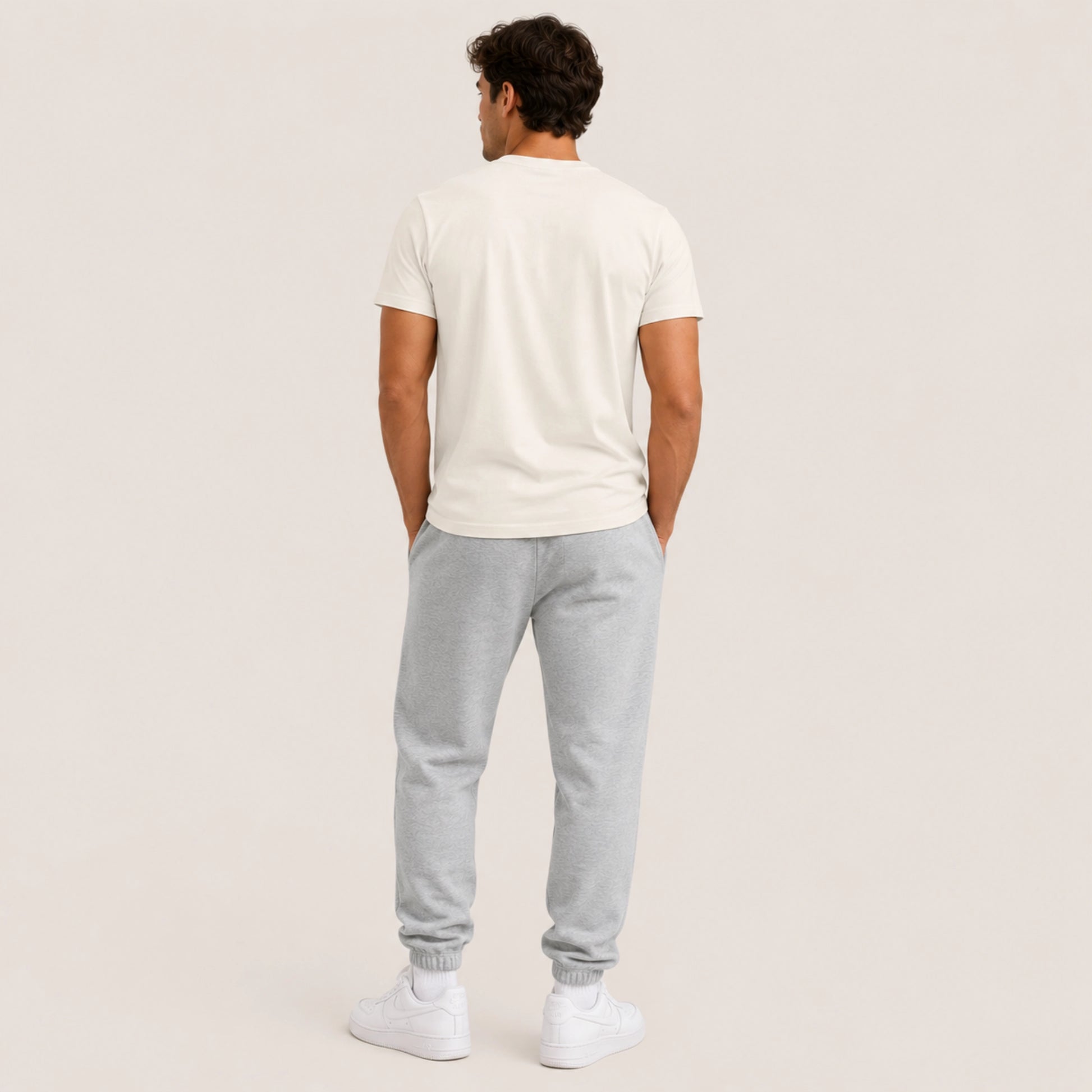 Man wearing a white t-shirt and gray sweatpants on a beige background