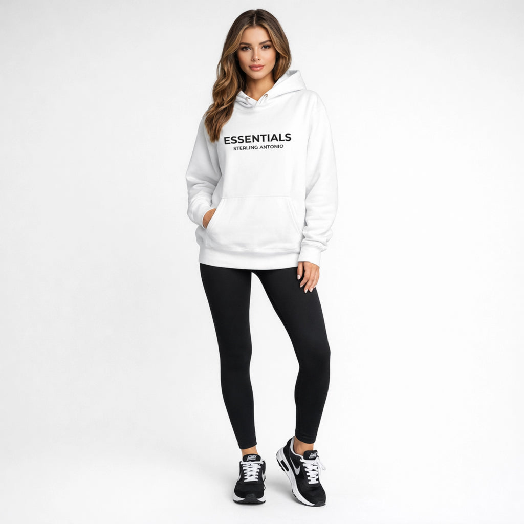 Woman wearing a white hoodie with 'ESSENTIALS' text and black leggings on a white background