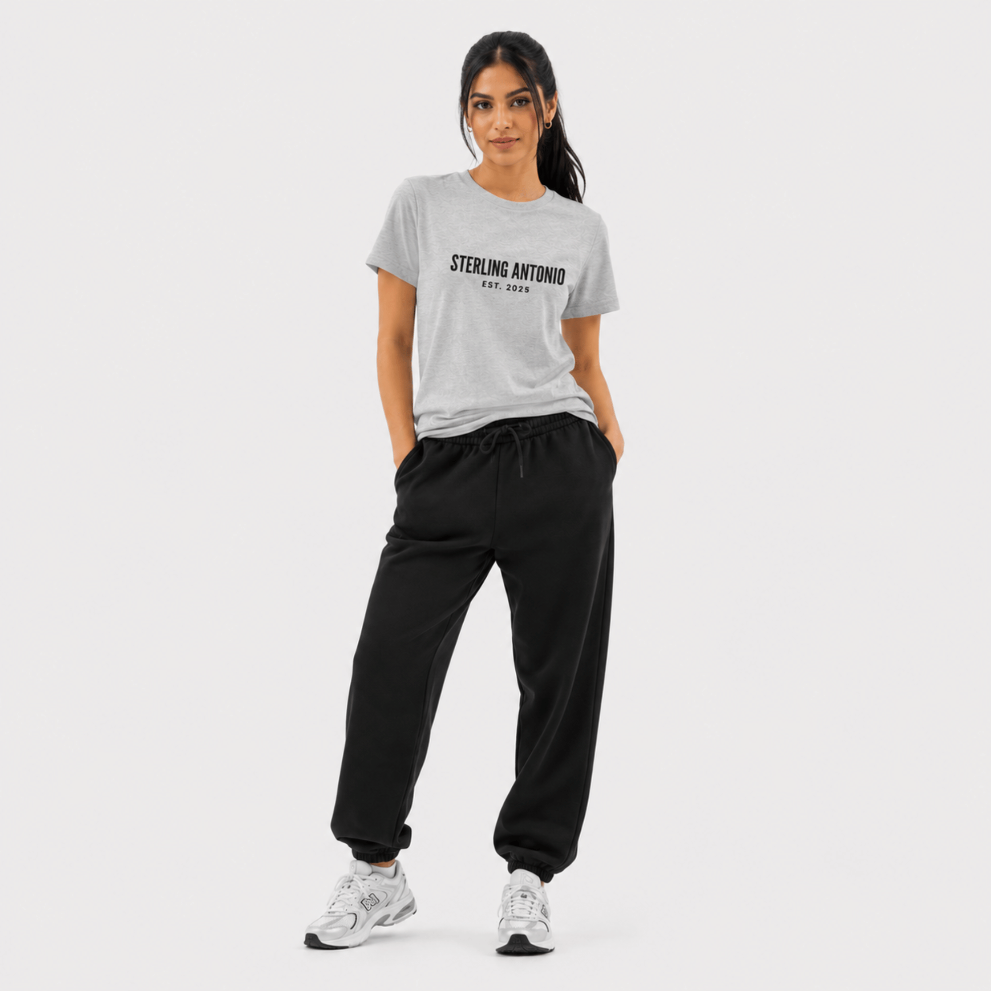 Woman wearing a gray t-shirt with 'Sterling Antonio' text and black pants on a white background