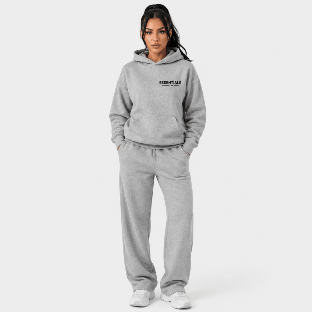 Female model wearing Sterling Antonio carbon grey essentials hoodie and matching sweatpants on light grey background