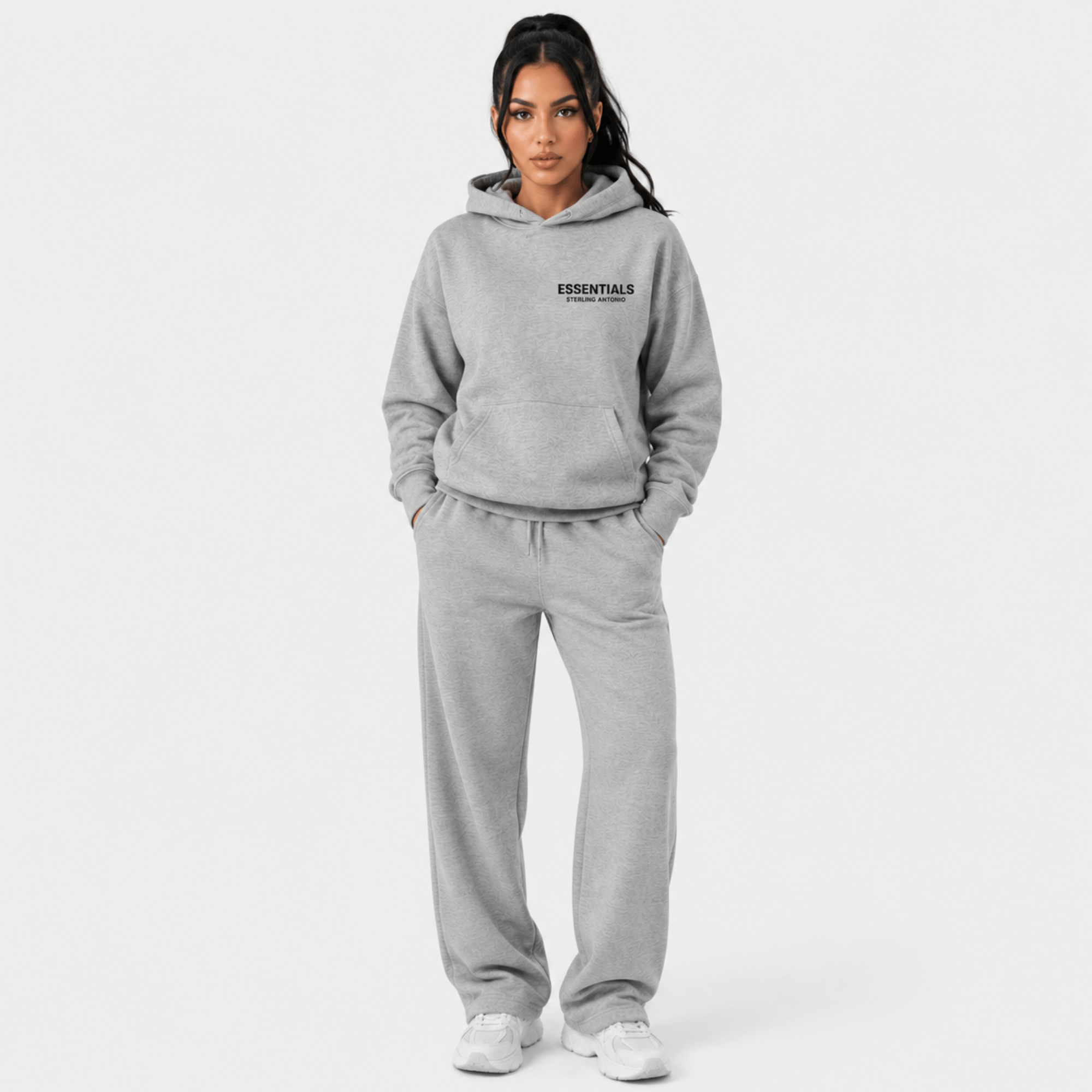 Female model wearing Sterling Antonio carbon grey essentials hoodie and matching sweatpants on light grey background
