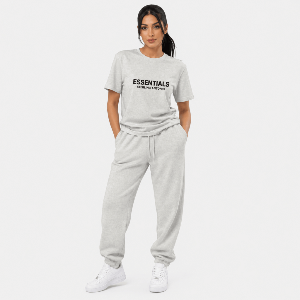 Female model wearing grey Essentials Sterling Antonio t-shirt with matching sweatpants and white sneakers against light grey background