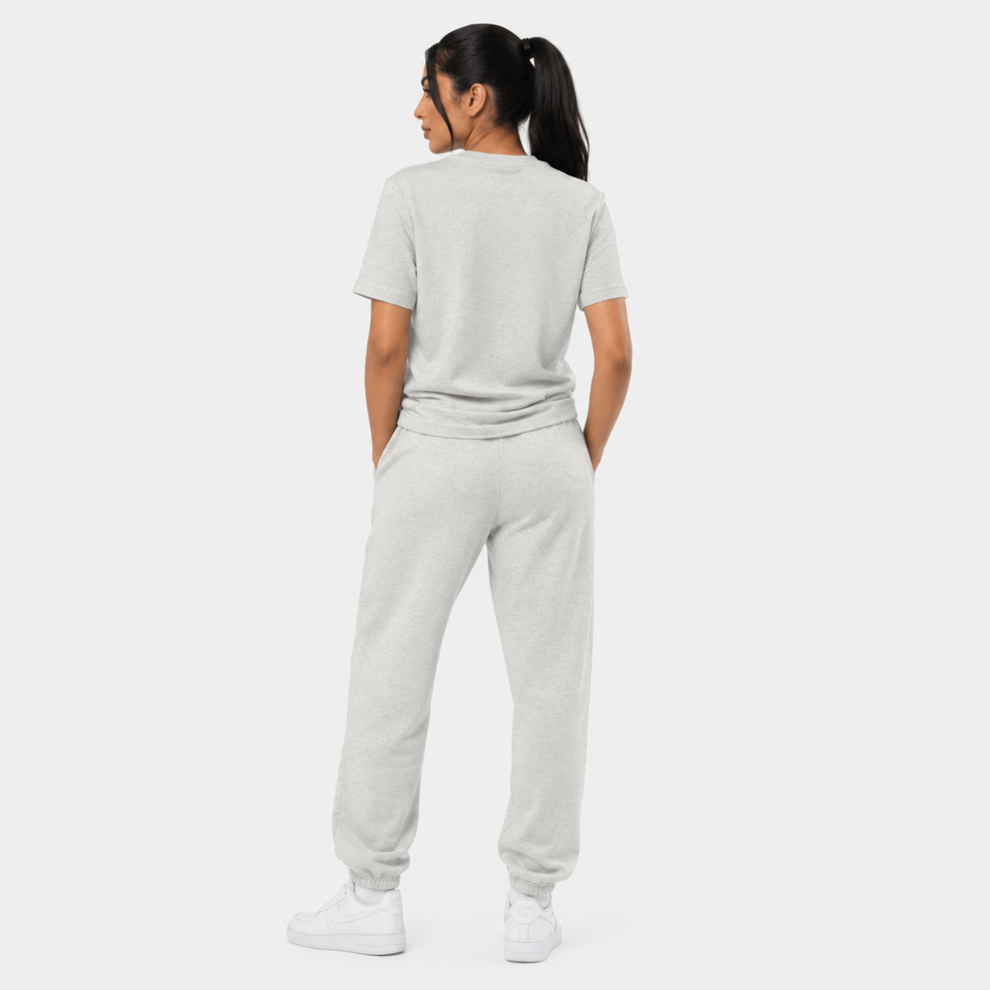 Rear view of female model wearing grey Sterling Antonio essentials t-shirt with matching sweatpants and white sneakers