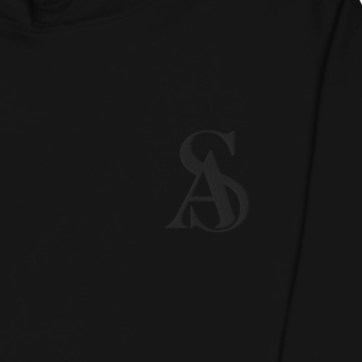 Tonal black SA monogram embroidered on the chest of The Black Label Hoodie