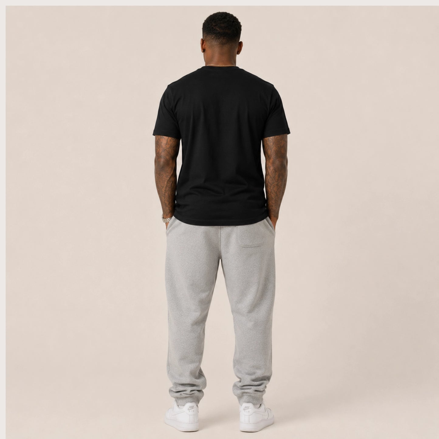 Person wearing a black t-shirt and gray sweatpants on a beige background