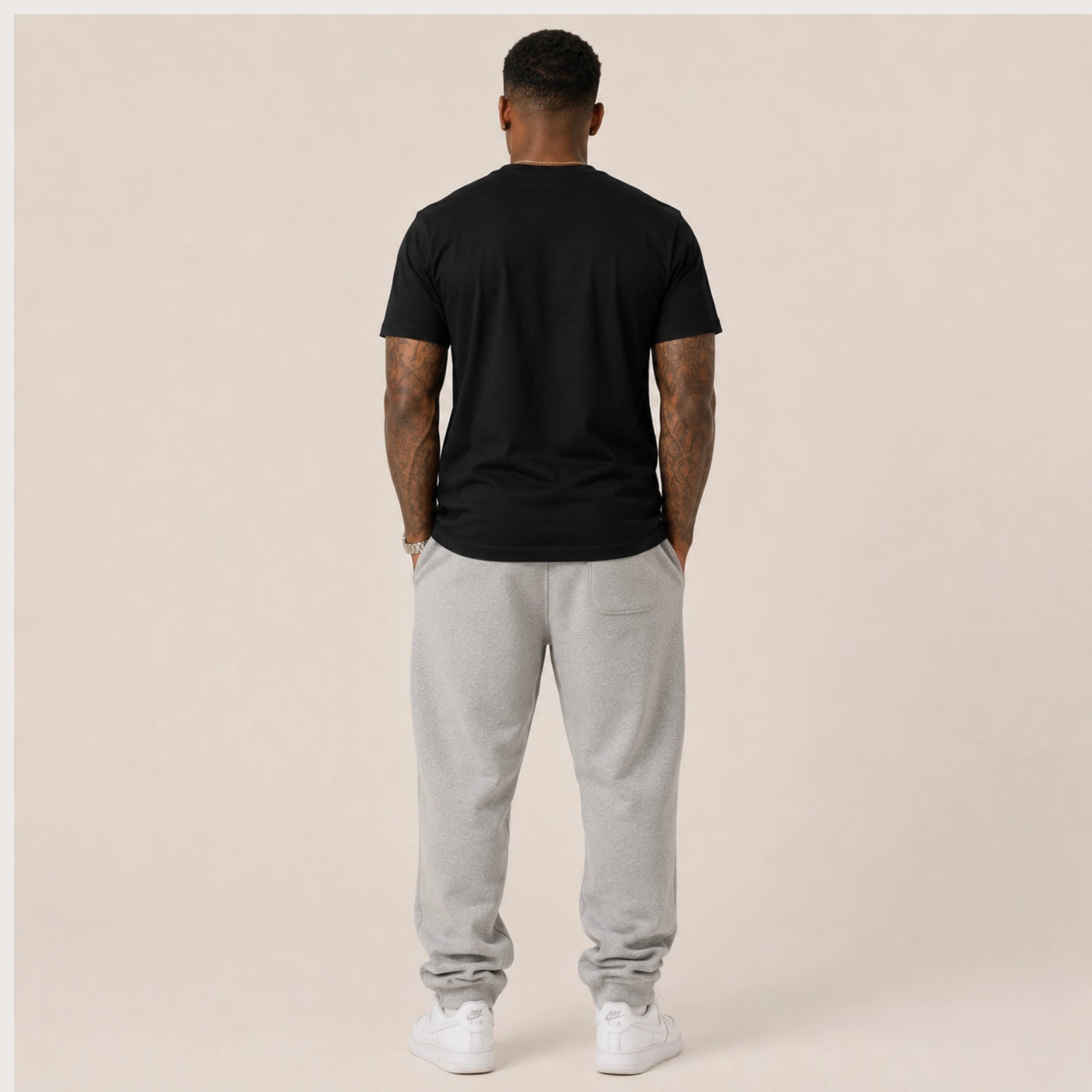 Person wearing a black t-shirt and gray sweatpants on a beige background
