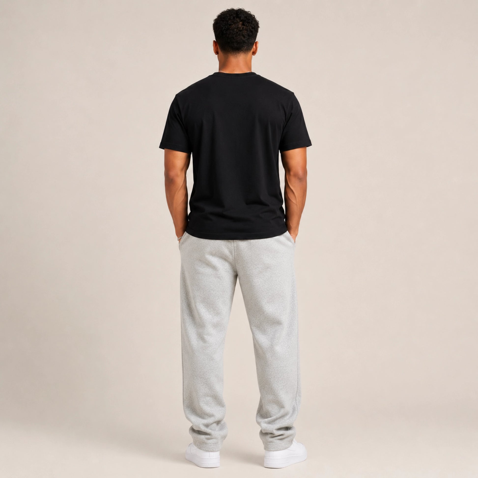 Person wearing a black t-shirt and gray sweatpants on a beige background