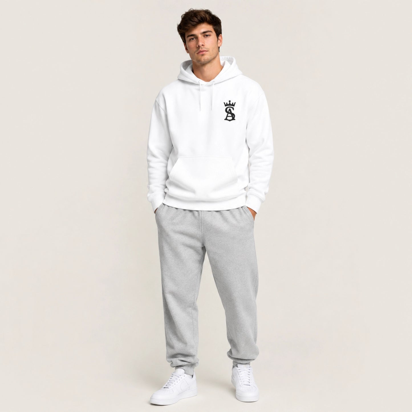 Man wearing a white hoodie and gray sweatpants on a plain background