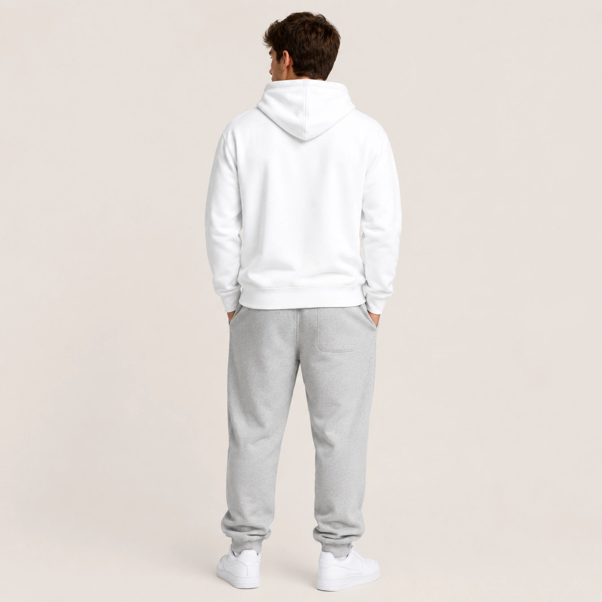 Person wearing a white hoodie and gray sweatpants on a beige background
