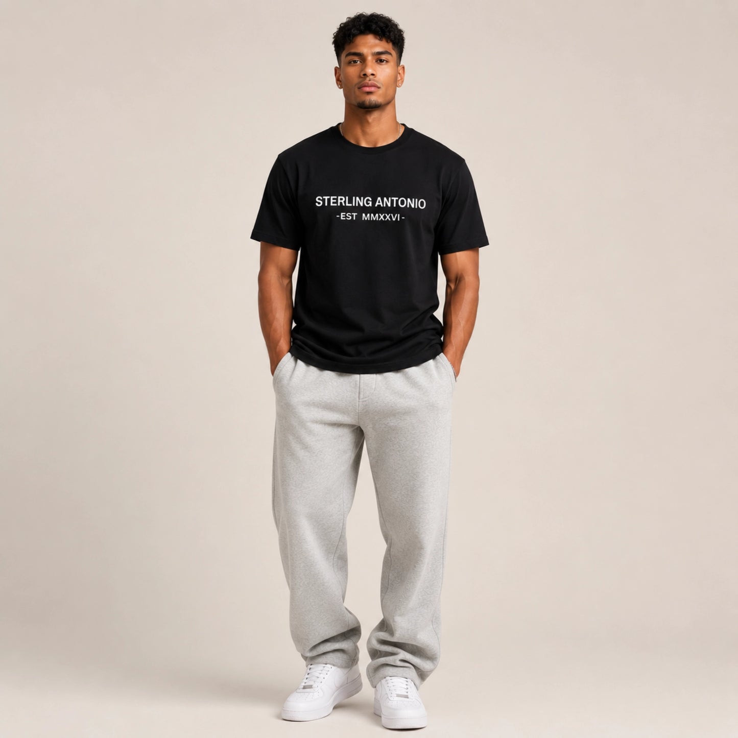 Man wearing a black t-shirt with text and gray sweatpants on a beige background
