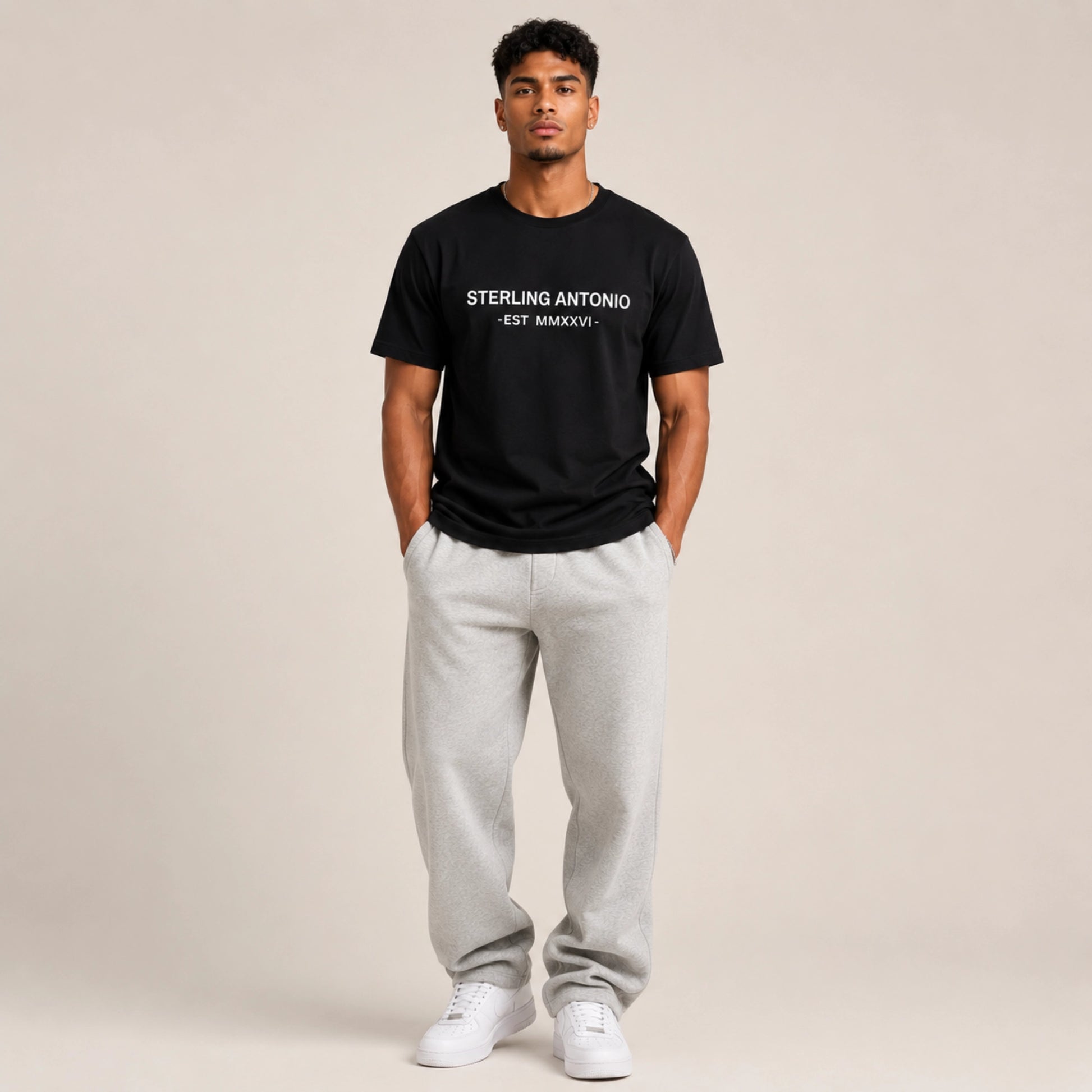 Man wearing a black t-shirt with text and gray sweatpants on a beige background