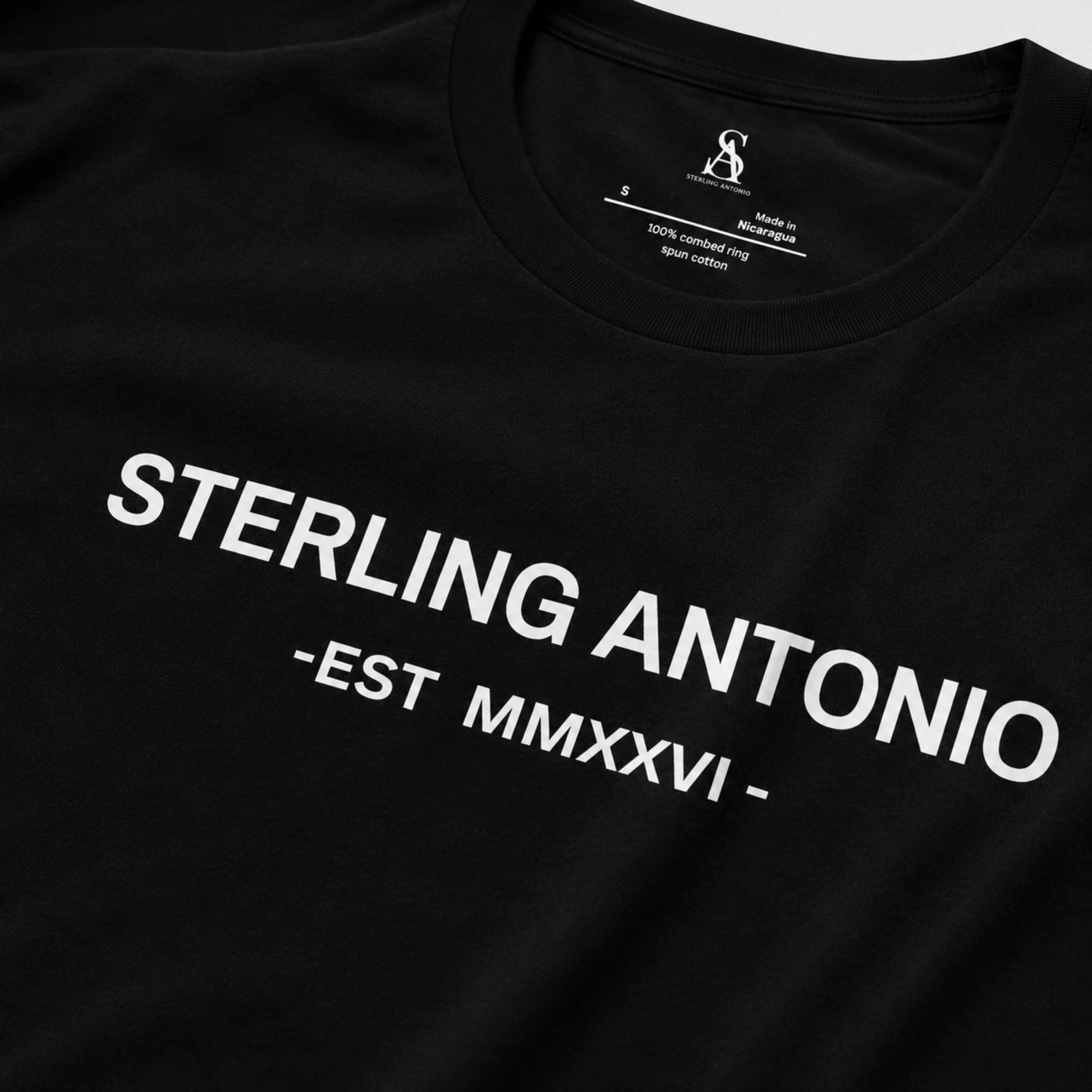 Black t-shirt with 'STERLING ANTONIO EST MMXXVI' text on a gray background